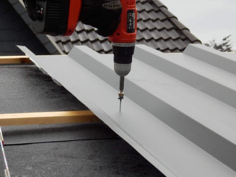 Professionele installatie van golfplaten op een dakspant met behulp van een accuboormachine